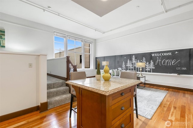 kitchen featuring light wood finished floors, brown cabinets, a breakfast bar, and baseboards