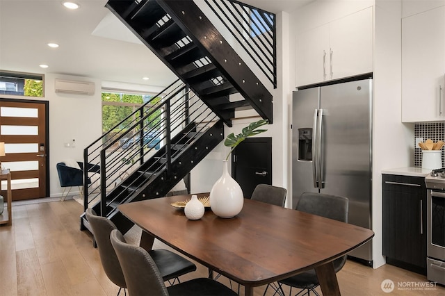 dining area with recessed lighting, light wood-style flooring, stairs, and a wall mounted AC