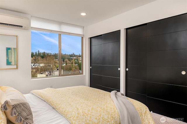 bedroom featuring recessed lighting, multiple closets, and a wall mounted AC