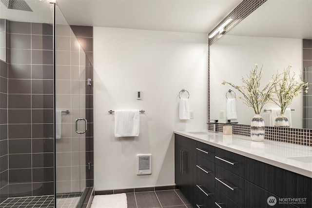 bathroom featuring a shower stall, double vanity, tile patterned floors, and a sink