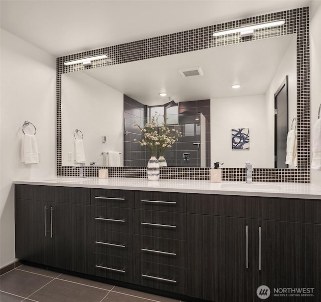 bathroom featuring tile patterned flooring, double vanity, visible vents, and a sink