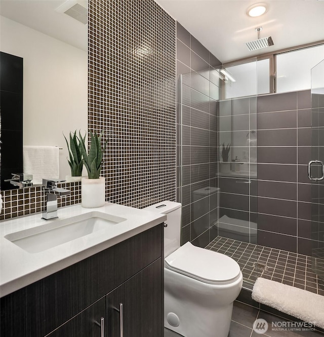 bathroom featuring visible vents, a tile shower, decorative backsplash, tile walls, and toilet