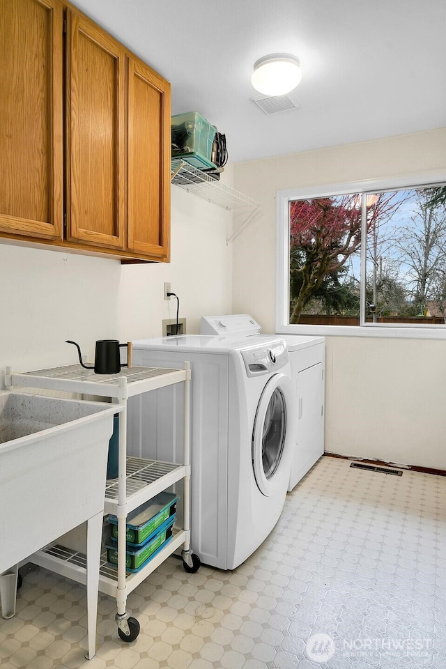 laundry room with cabinet space, light floors, and washing machine and dryer