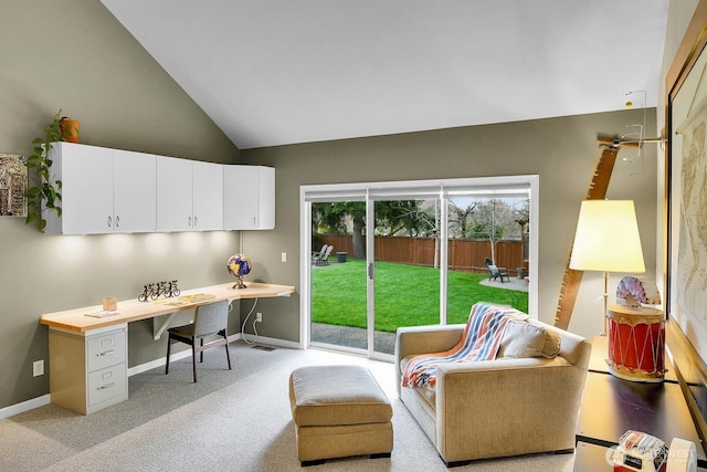 office area featuring lofted ceiling, light colored carpet, baseboards, and built in study area