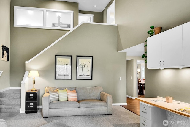 living room featuring baseboards and a towering ceiling