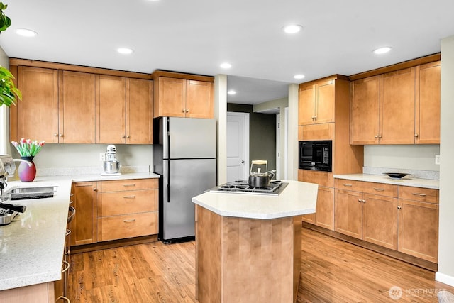 kitchen with gas stovetop, freestanding refrigerator, a sink, black microwave, and light wood-type flooring