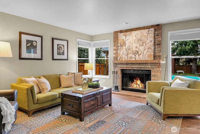 living area featuring a wealth of natural light, a brick fireplace, and wood finished floors