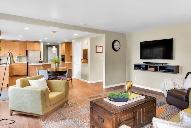 living area with recessed lighting, baseboards, and light wood-style flooring