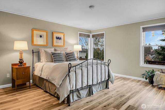 bedroom with multiple windows, light wood-type flooring, and ornamental molding