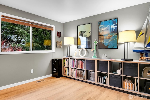 living area featuring visible vents, baseboards, and wood finished floors