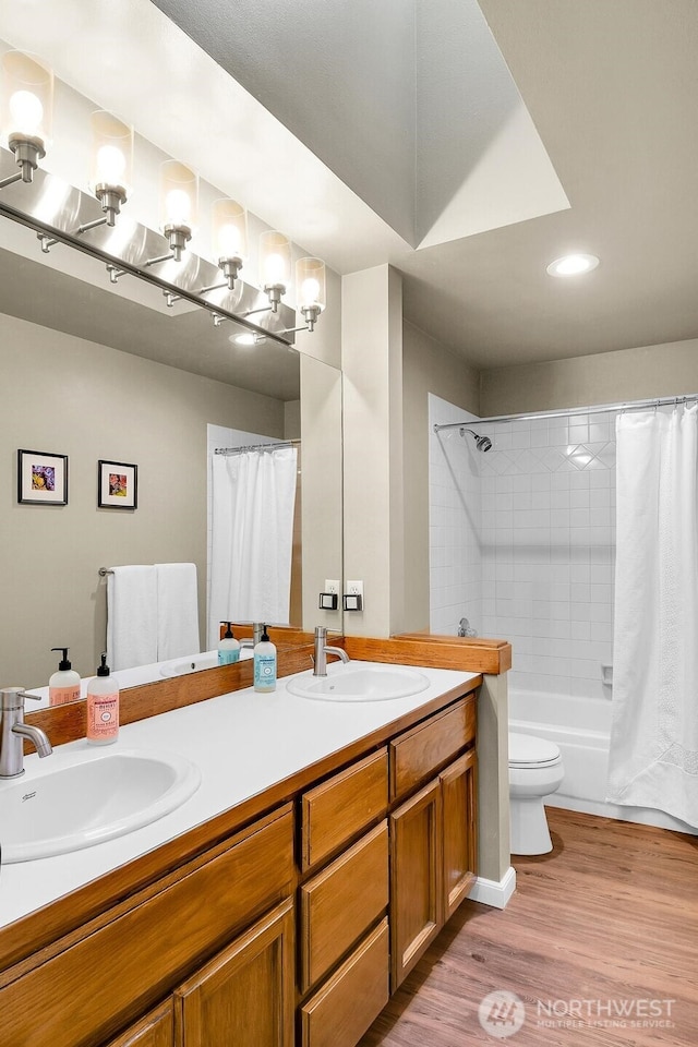 bathroom with double vanity, toilet, wood finished floors, and a sink