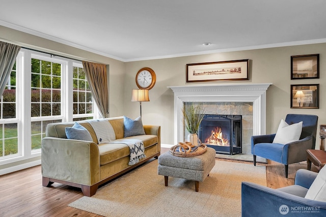 living room featuring a tiled fireplace, wood finished floors, baseboards, and ornamental molding