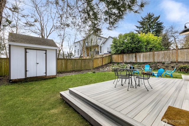 wooden terrace featuring an outbuilding, a yard, and a fenced backyard