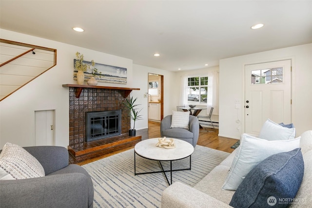 living area with a tiled fireplace, recessed lighting, wood finished floors, and a baseboard radiator