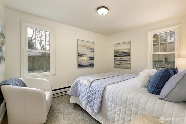 bedroom with a baseboard heating unit and multiple windows