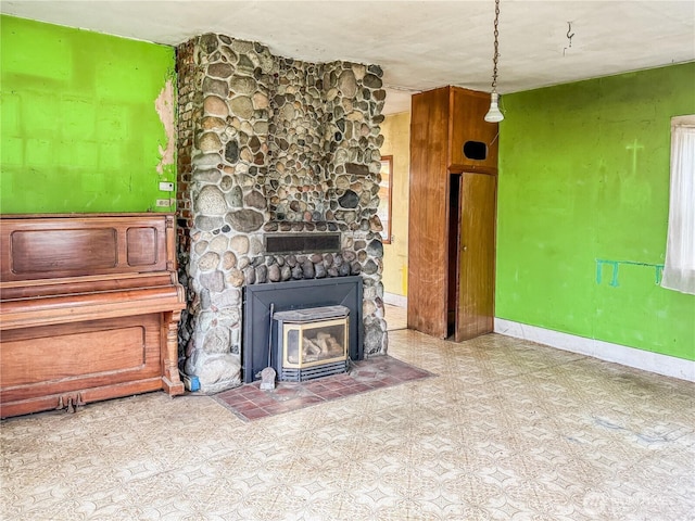 unfurnished living room featuring baseboards and a wood stove