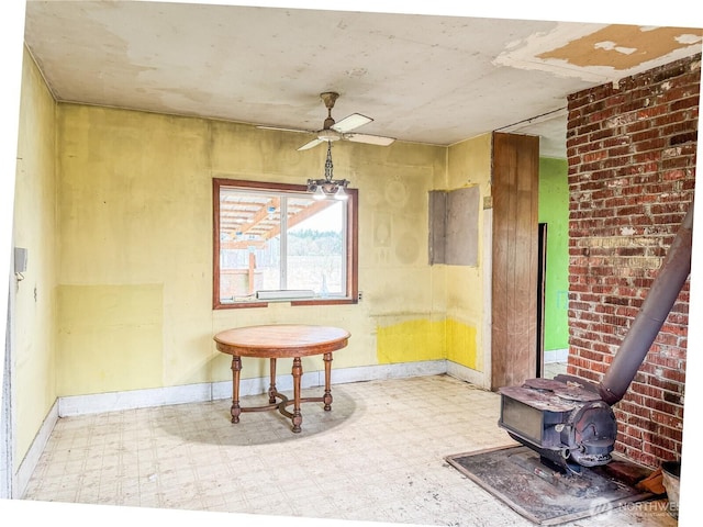 dining room with tile patterned floors, baseboards, a ceiling fan, and a wood stove