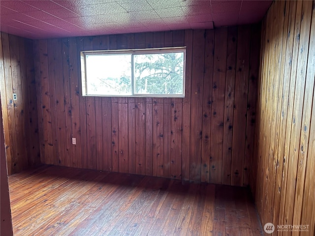 empty room with hardwood / wood-style floors and wood walls