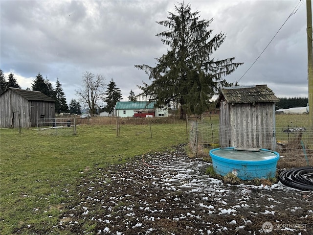 view of yard featuring a storage unit, an outdoor structure, and fence