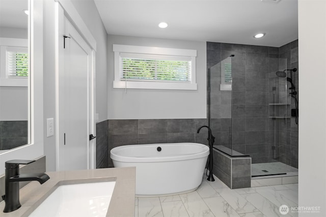 full bath featuring a freestanding tub, marble finish floor, recessed lighting, a shower stall, and vanity