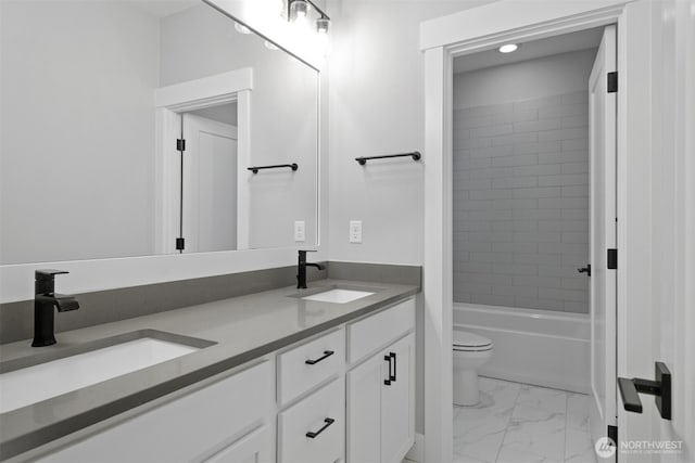 bathroom with double vanity, marble finish floor, toilet, and a sink