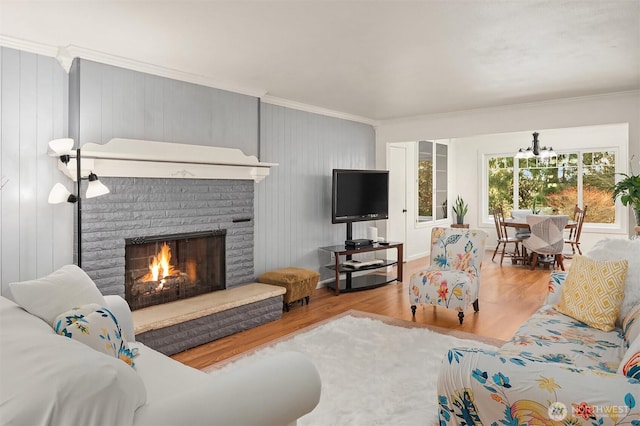 living room featuring wood finished floors, a notable chandelier, a fireplace, and ornamental molding