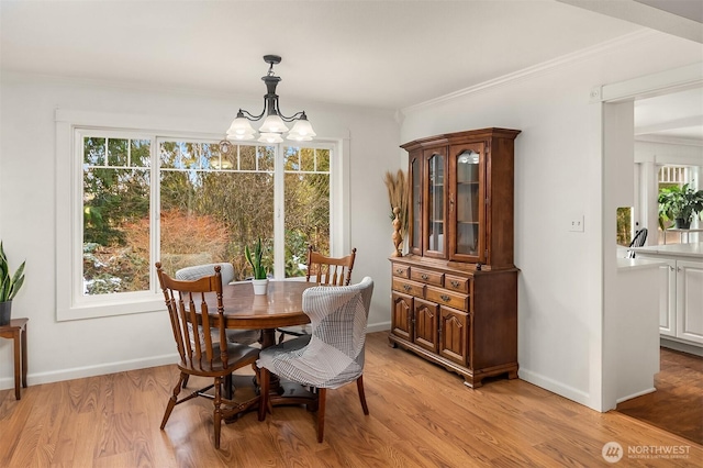 dining area featuring light wood-type flooring, baseboards, a chandelier, and crown molding