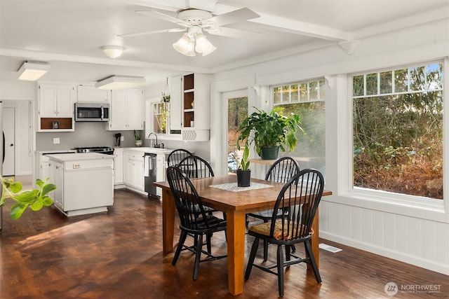 dining area featuring a wainscoted wall, beam ceiling, and a ceiling fan