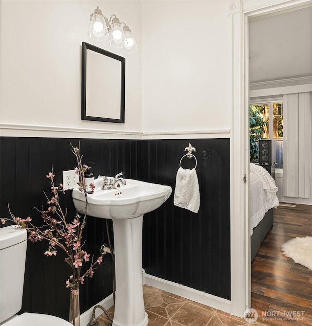 half bathroom with a wainscoted wall, toilet, and wood finished floors