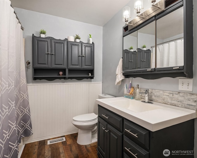 full bathroom with vanity, wood finished floors, visible vents, wainscoting, and toilet