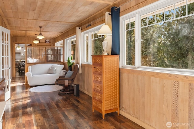 living area with a ceiling fan, wooden ceiling, wood finished floors, and wood walls