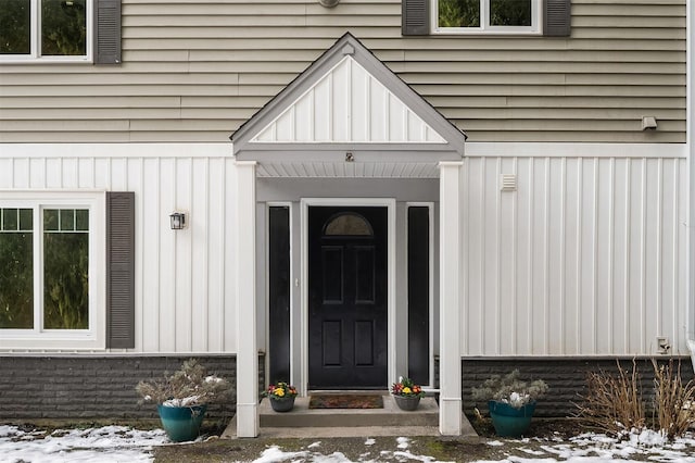 snow covered property entrance with board and batten siding