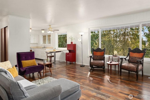 living area featuring baseboards, a ceiling fan, and dark wood-style flooring