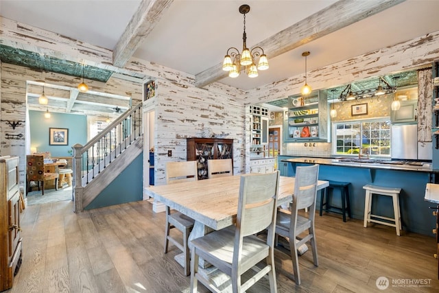 dining area with stairs, hardwood / wood-style flooring, an inviting chandelier, and beam ceiling