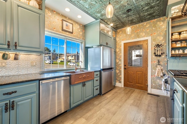 kitchen featuring wallpapered walls, baseboards, light wood-type flooring, appliances with stainless steel finishes, and an ornate ceiling