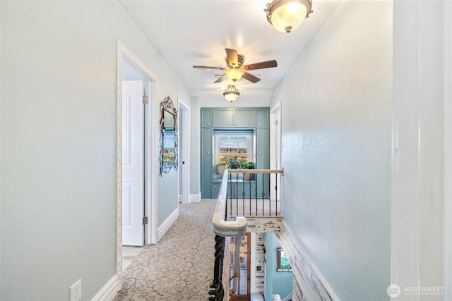 hallway with baseboards and light carpet