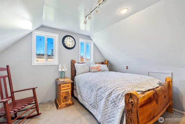 bedroom featuring lofted ceiling, rail lighting, and light colored carpet