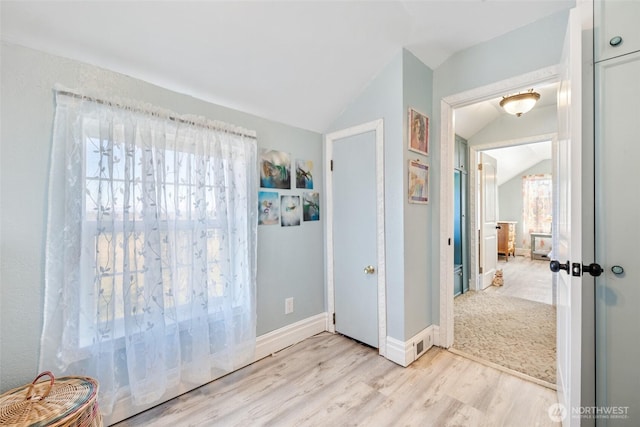 unfurnished bedroom featuring baseboards, lofted ceiling, and light wood-style floors