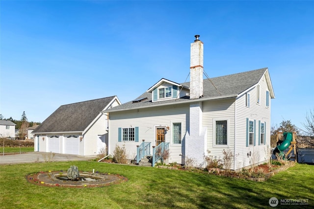 view of front of house with an outbuilding, driveway, a chimney, a front lawn, and a garage