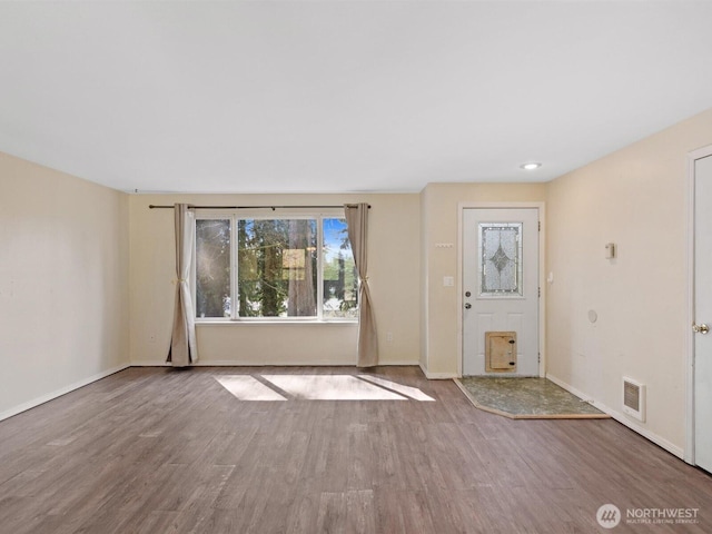 foyer entrance featuring visible vents, baseboards, and wood finished floors