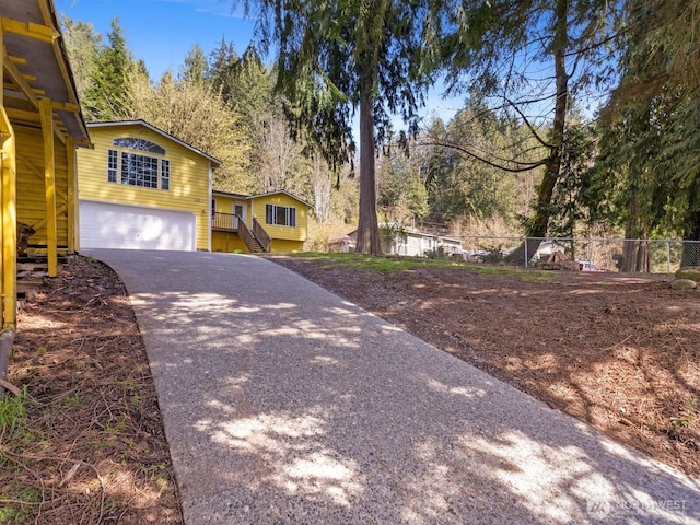 view of front of home with concrete driveway, a garage, fence, and stairs