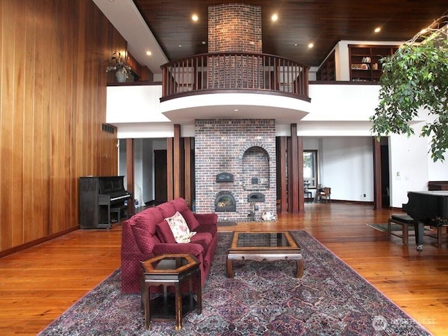 living room featuring wooden walls, recessed lighting, a high ceiling, and wood-type flooring