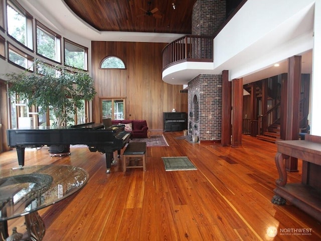 living area featuring hardwood / wood-style floors, wooden walls, a high ceiling, wooden ceiling, and stairs