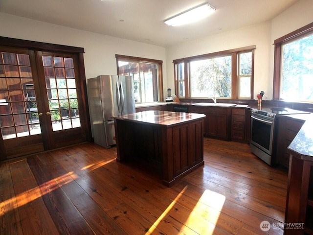 kitchen featuring dark wood-style floors, french doors, stainless steel appliances, and a center island