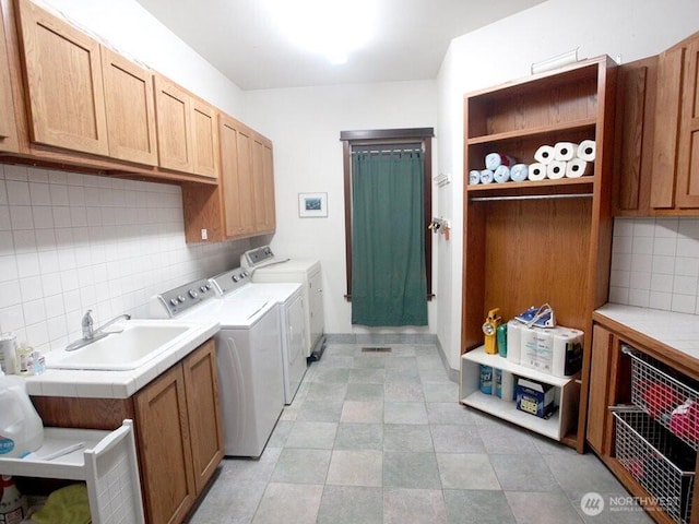 laundry room featuring washing machine and clothes dryer, cabinet space, and a sink