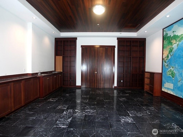 interior space with wooden ceiling, marble finish floor, and a raised ceiling