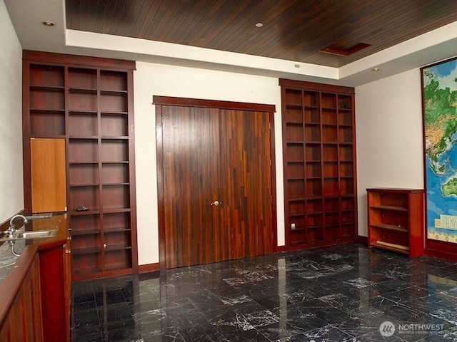 interior space featuring built in shelves, wood ceiling, and a raised ceiling