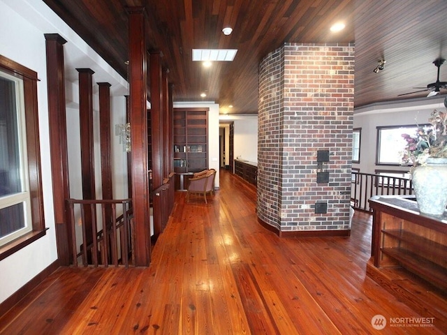 corridor with visible vents, an upstairs landing, hardwood / wood-style floors, and wooden ceiling