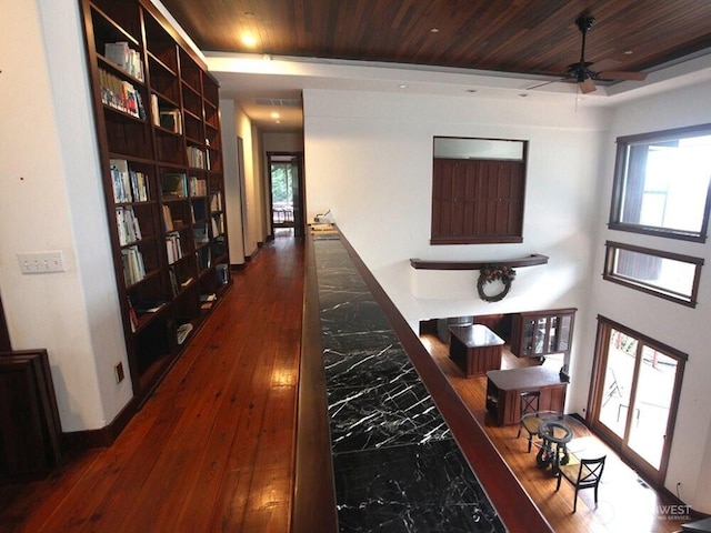 hallway with visible vents, baseboards, dark wood-type flooring, and wooden ceiling