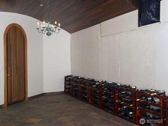 wine room featuring baseboards, vaulted ceiling, wooden ceiling, arched walkways, and stone finish floor